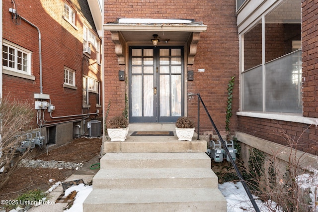 property entrance with french doors, brick siding, and central air condition unit