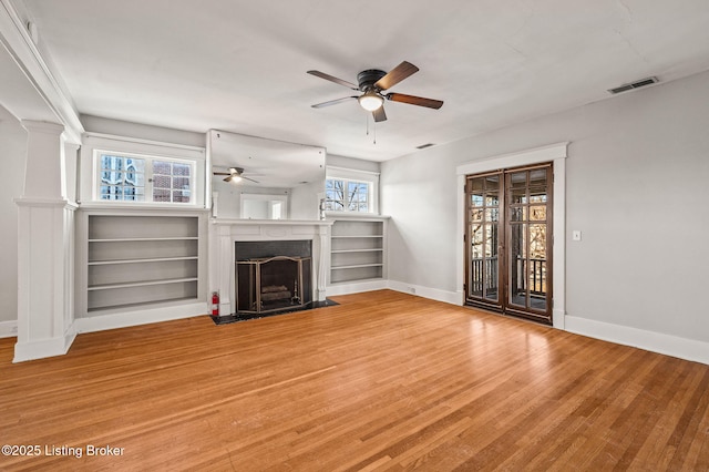 unfurnished living room featuring light wood-style flooring, a fireplace with flush hearth, visible vents, a ceiling fan, and baseboards