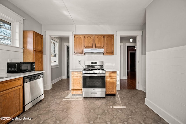 kitchen featuring appliances with stainless steel finishes, brown cabinets, light countertops, and under cabinet range hood