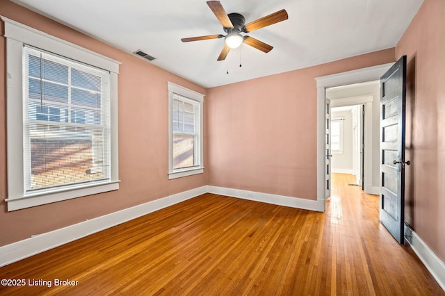 spare room featuring a ceiling fan, baseboards, visible vents, and wood finished floors