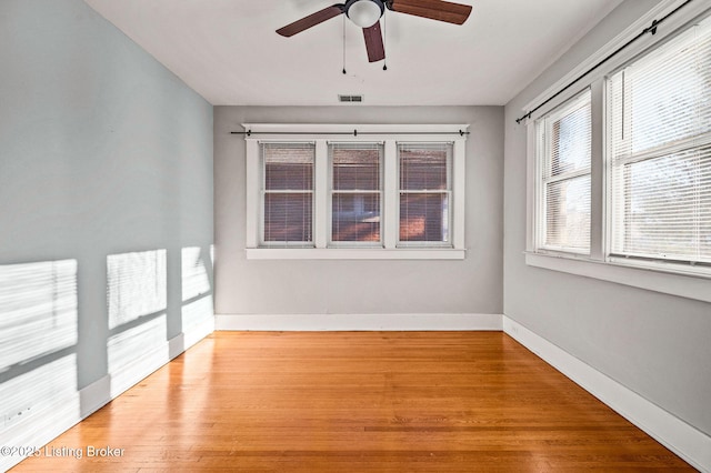 unfurnished room with ceiling fan, light wood finished floors, visible vents, and baseboards