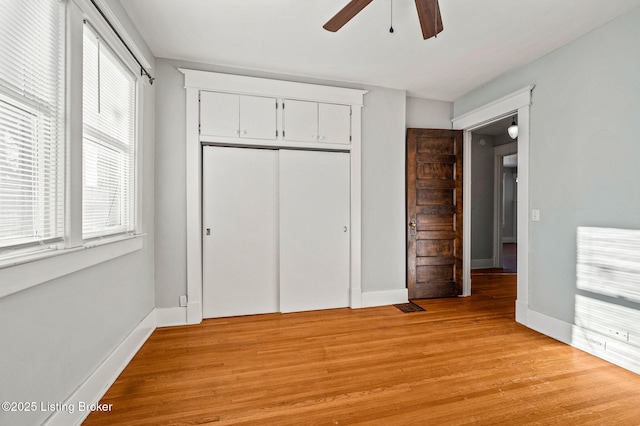 unfurnished bedroom with light wood finished floors, ceiling fan, baseboards, and a closet