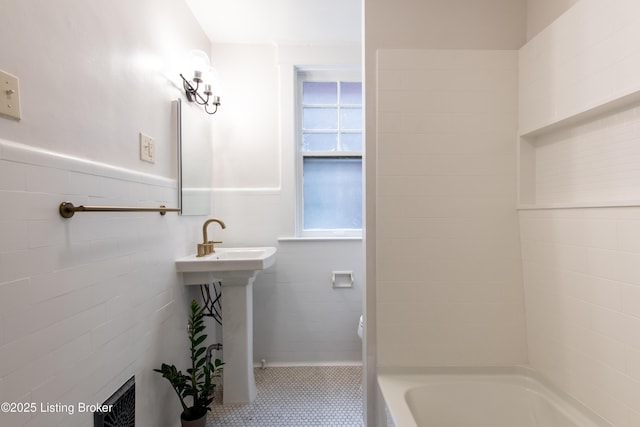 bathroom with toilet, shower / tub combination, tile walls, and wainscoting