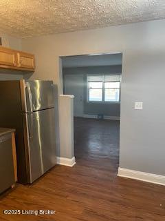 kitchen featuring stainless steel fridge, dark hardwood / wood-style floors, and a textured ceiling