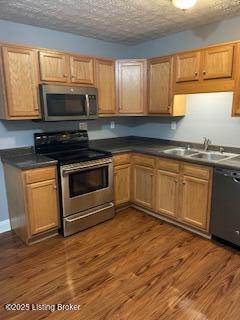 kitchen featuring dark hardwood / wood-style flooring, sink, stainless steel appliances, and a textured ceiling