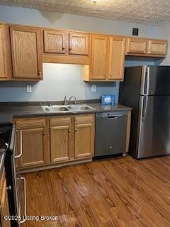 kitchen featuring appliances with stainless steel finishes, sink, a textured ceiling, and dark hardwood / wood-style floors