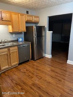 kitchen featuring dishwasher, sink, stainless steel fridge, and dark hardwood / wood-style floors