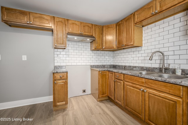 kitchen with sink, decorative backsplash, and light wood-type flooring