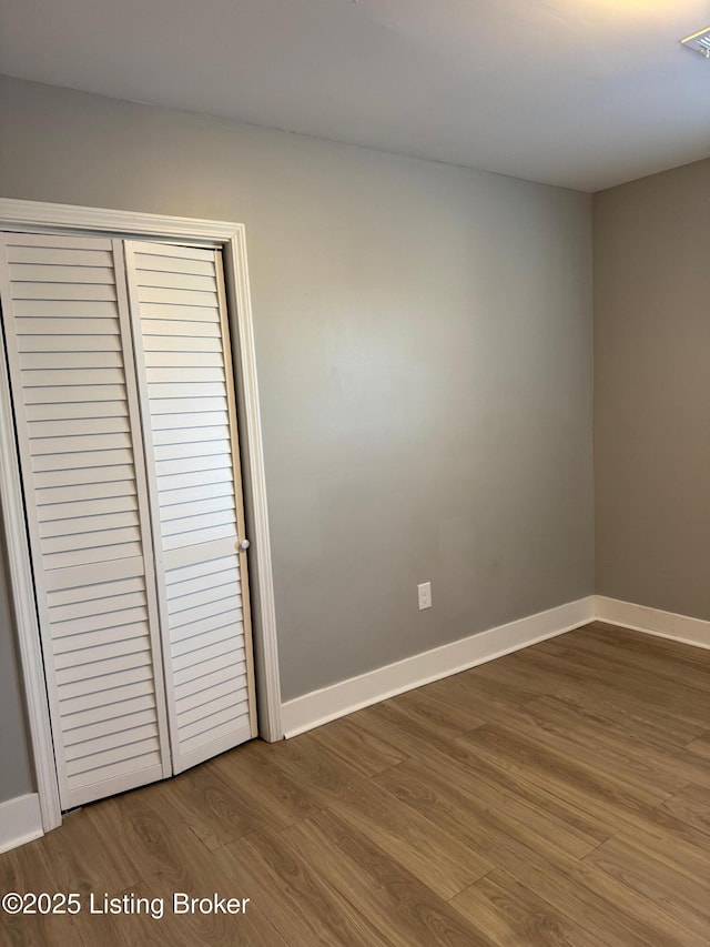 unfurnished bedroom featuring wood-type flooring and a closet