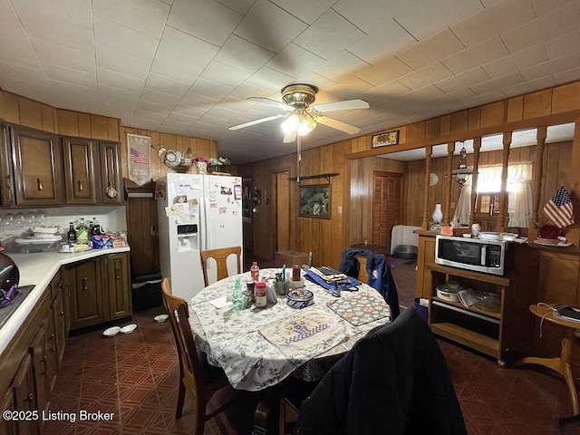 dining space featuring ceiling fan and wooden walls