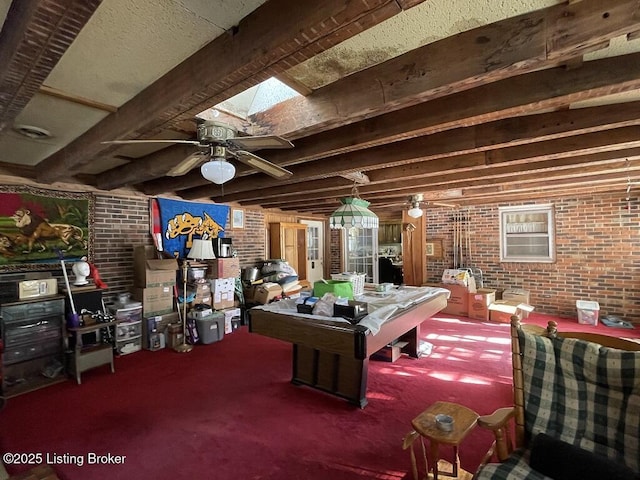 recreation room featuring ceiling fan, carpet, beam ceiling, and a skylight