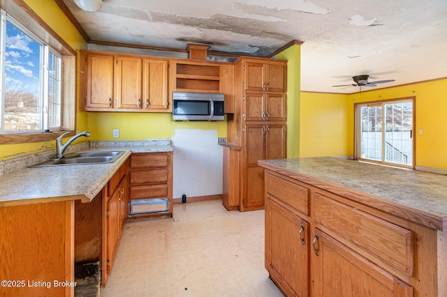 kitchen featuring ceiling fan, sink, and crown molding