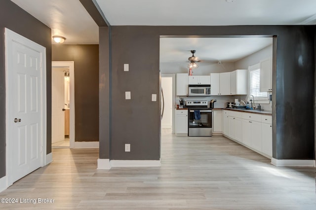 kitchen featuring light wood-type flooring, stainless steel appliances, white cabinets, and sink