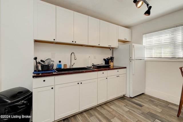 kitchen with white fridge, light hardwood / wood-style floors, white cabinets, and sink