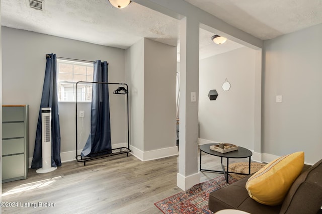 living area featuring a textured ceiling and light hardwood / wood-style flooring