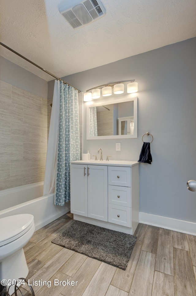 full bathroom featuring a textured ceiling, toilet, vanity, and shower / tub combo with curtain