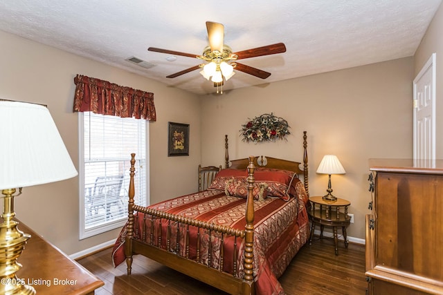 bedroom with ceiling fan, dark wood-type flooring, and a textured ceiling