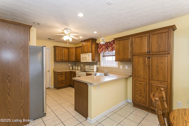 kitchen featuring sink, white appliances, kitchen peninsula, and tasteful backsplash