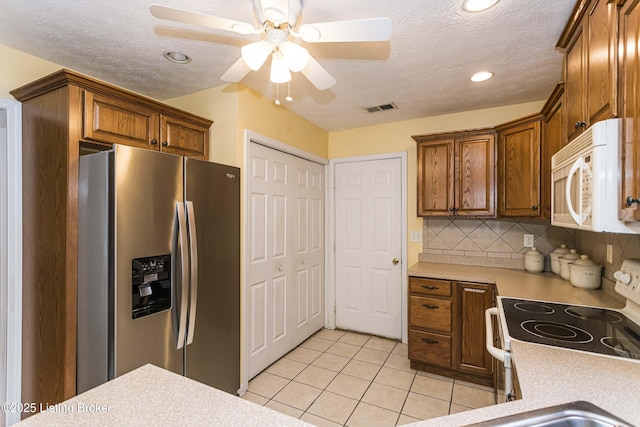 kitchen with white appliances, a textured ceiling, tasteful backsplash, ceiling fan, and light tile patterned flooring