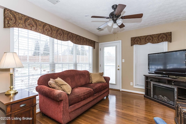 living room featuring dark wood-type flooring, a textured ceiling, and ceiling fan