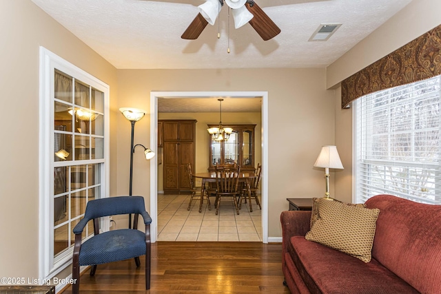 living room featuring ceiling fan with notable chandelier, hardwood / wood-style flooring, and a textured ceiling