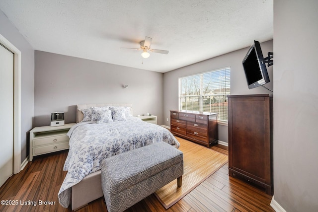 bedroom with dark hardwood / wood-style flooring, a textured ceiling, and ceiling fan