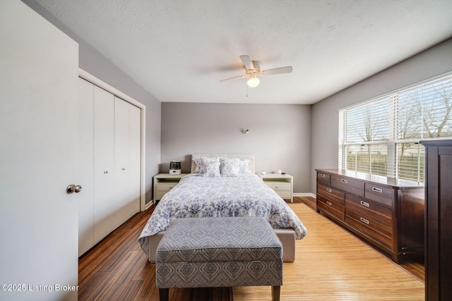 bedroom featuring hardwood / wood-style floors, a textured ceiling, ceiling fan, and a closet