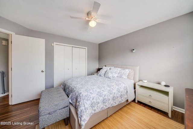 bedroom with ceiling fan, radiator heating unit, hardwood / wood-style floors, and a closet