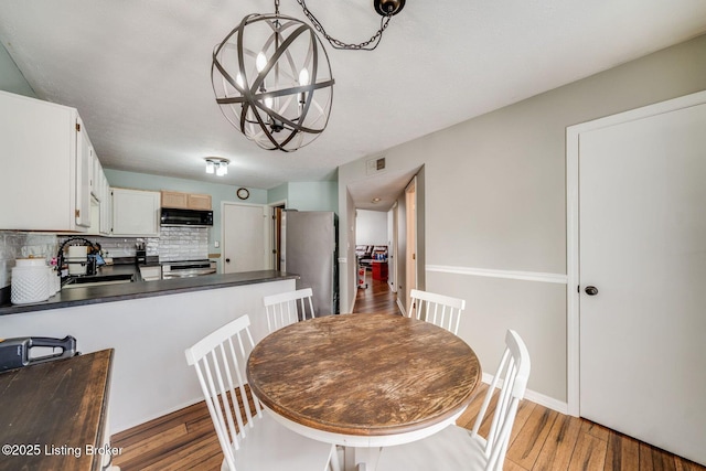 dining area with an inviting chandelier, sink, and dark hardwood / wood-style floors