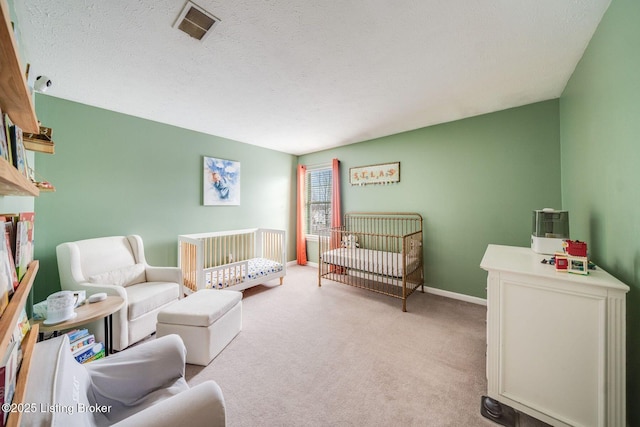 carpeted bedroom with a crib and a textured ceiling