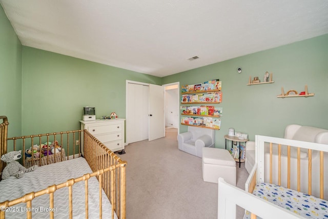 bedroom with a nursery area, light colored carpet, and a closet