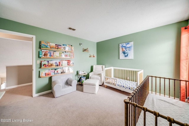 carpeted bedroom featuring a nursery area