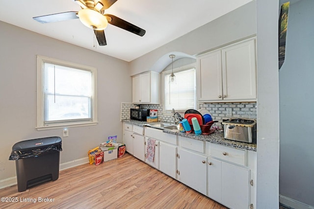 kitchen featuring tasteful backsplash, light hardwood / wood-style floors, pendant lighting, sink, and white cabinetry