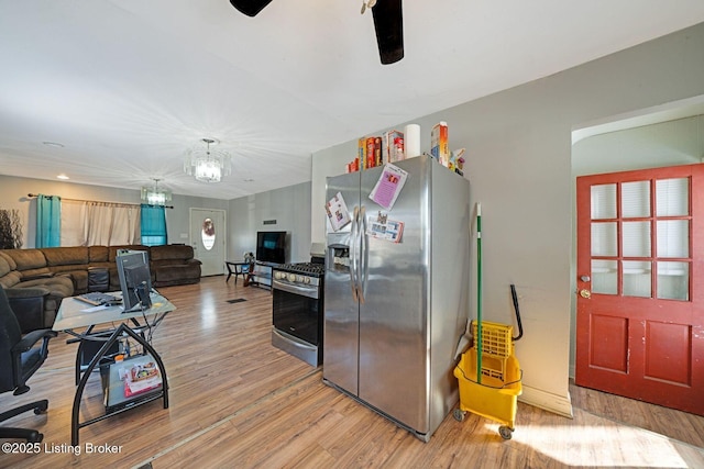 kitchen with appliances with stainless steel finishes, ceiling fan with notable chandelier, and wood-type flooring