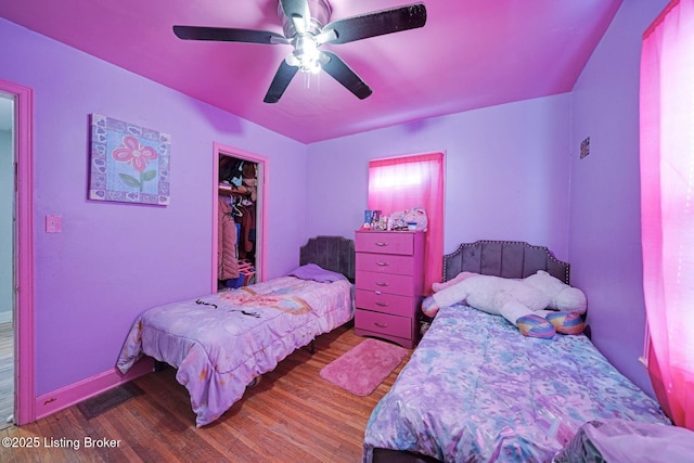 bedroom featuring ceiling fan, a closet, a spacious closet, and hardwood / wood-style floors