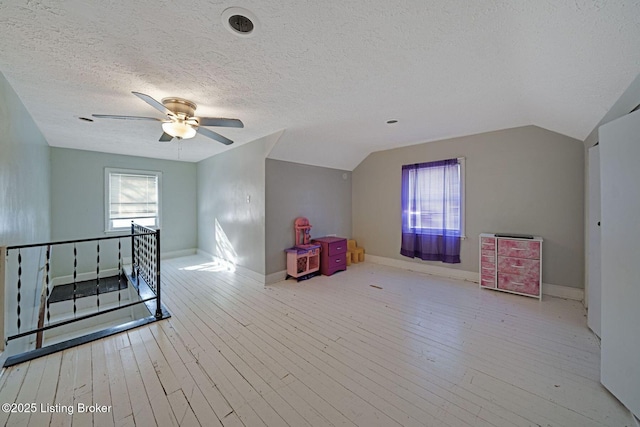 additional living space with ceiling fan, vaulted ceiling, a textured ceiling, and light hardwood / wood-style floors