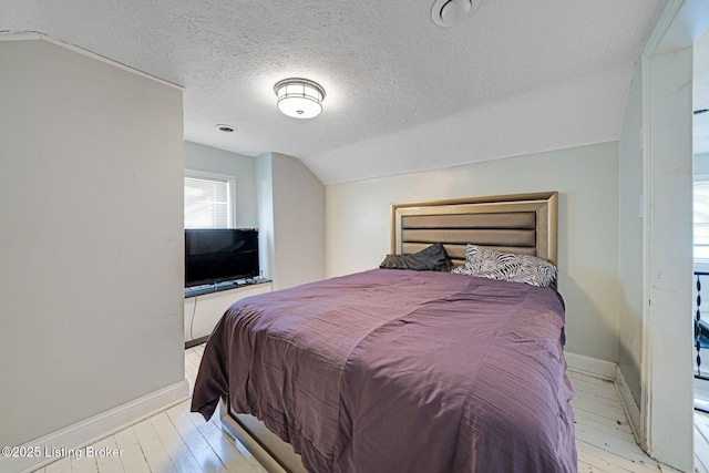 bedroom with a textured ceiling, lofted ceiling, and light wood-type flooring