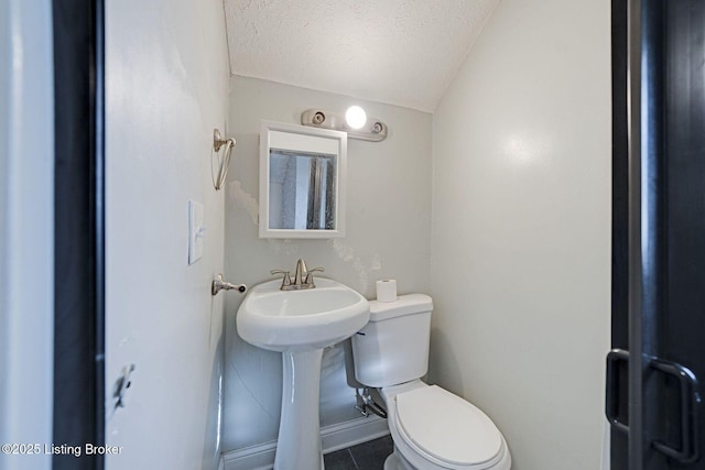 bathroom with a textured ceiling, toilet, tile patterned flooring, and lofted ceiling