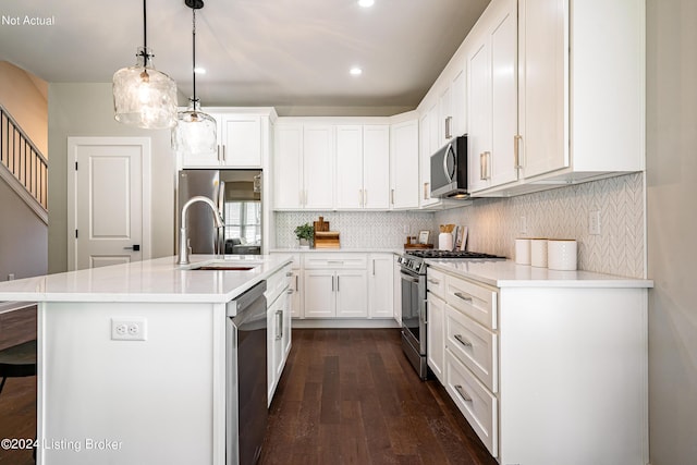 kitchen with hanging light fixtures, white cabinets, sink, stainless steel appliances, and a center island with sink