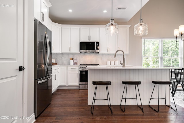 kitchen featuring a kitchen breakfast bar, pendant lighting, white cabinets, decorative backsplash, and stainless steel appliances