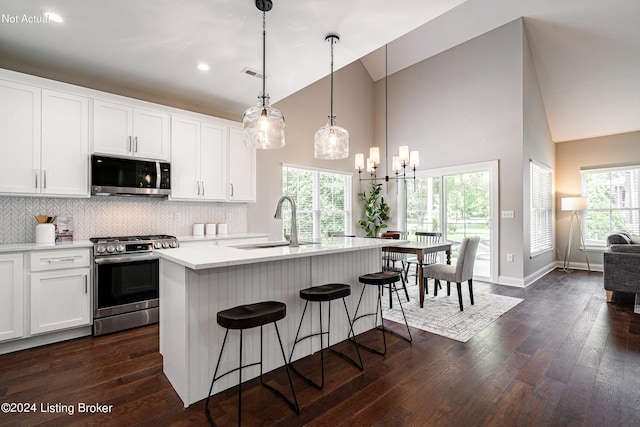 kitchen featuring white cabinets, decorative light fixtures, stainless steel appliances, an island with sink, and sink