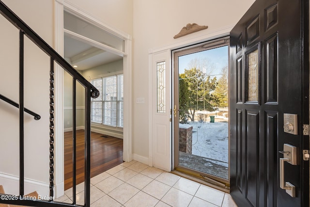 foyer entrance with stairs, baseboards, and light tile patterned flooring