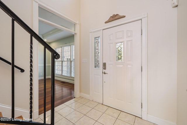 foyer with stairs, baseboards, and light tile patterned flooring