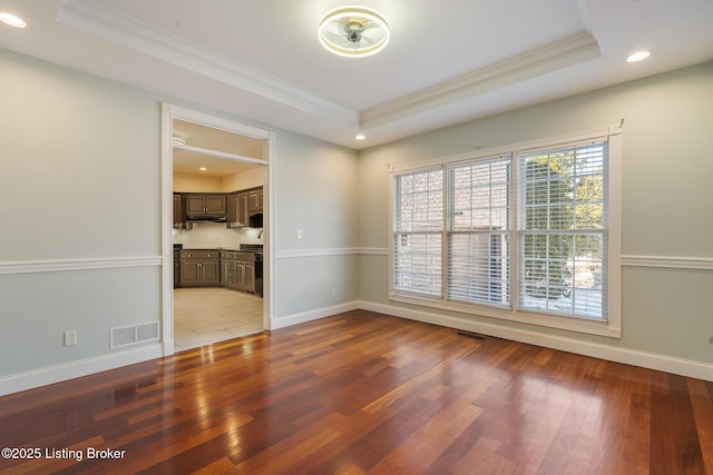 unfurnished room with crown molding, light wood-type flooring, and a tray ceiling