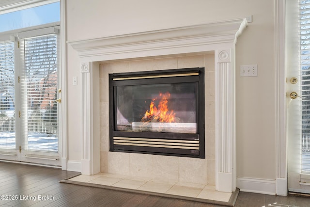 interior details with baseboards, wood finished floors, and a tile fireplace