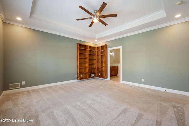 empty room featuring ornamental molding, light colored carpet, ceiling fan, and a tray ceiling