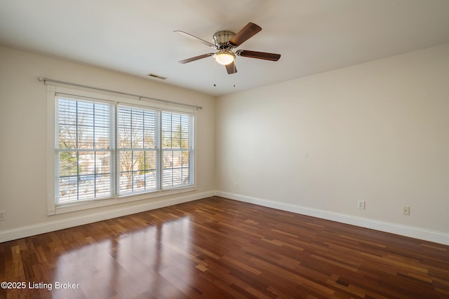 spare room with ceiling fan, wood finished floors, visible vents, and baseboards