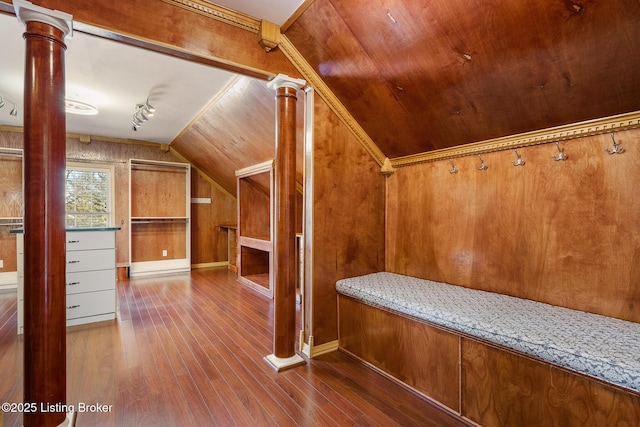 interior space featuring ornate columns, vaulted ceiling, wood finished floors, and wood walls