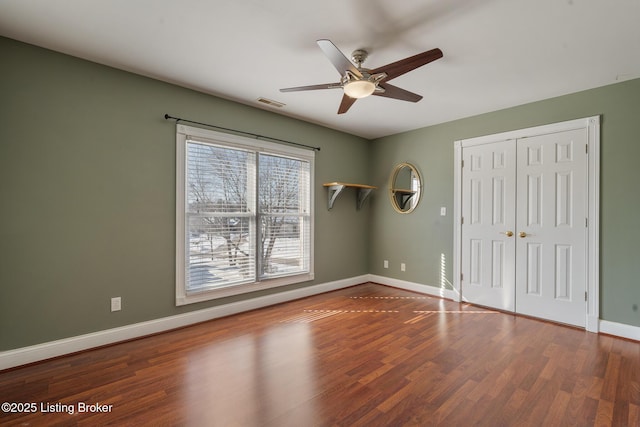 unfurnished bedroom featuring a closet, ceiling fan, baseboards, and wood finished floors