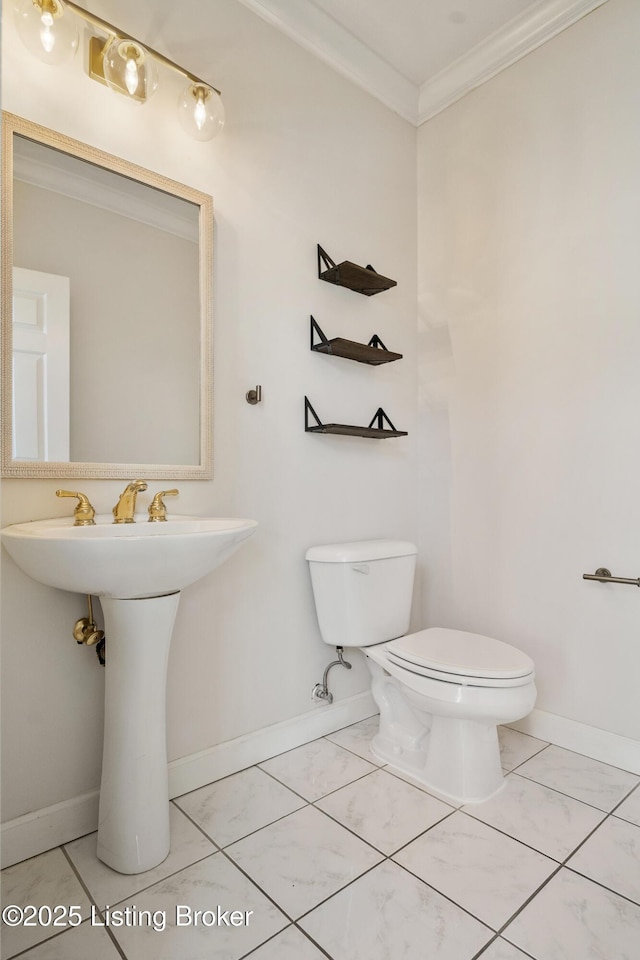 bathroom with ornamental molding, toilet, and baseboards